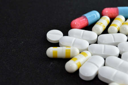 Bunch of pill capsules over black backgroundの写真素材