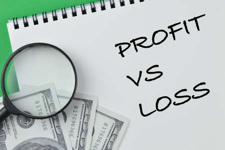 Magnifying glass, money banknotes and notebook written with PROFIT VS LOSSの写真素材