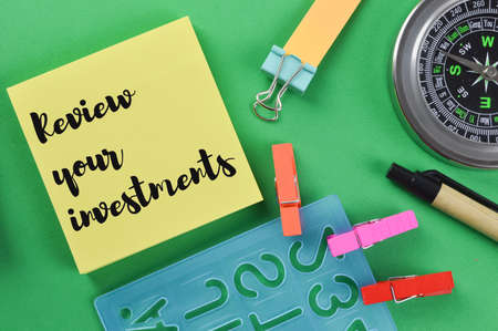 Memo note written with text REVIEW YOUR INVESTMENTS