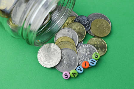 Stack of coins and alphabet beads with text SAVING