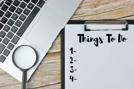 top view of magnifying glass, laptop and file written with THINGS TO DO.