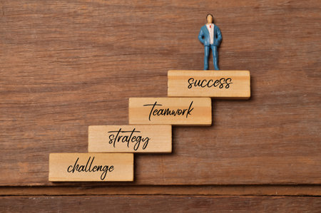 People miniature standing on wooden block written with CHALLENGE, STRATEGY, TEAMWORK and SUCCESS.の写真素材