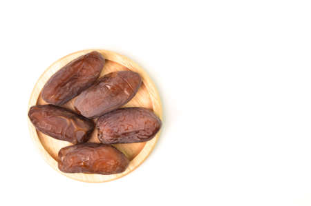 Top view of Dates on a wooden plate isolated on a white background with copy spaceの写真素材