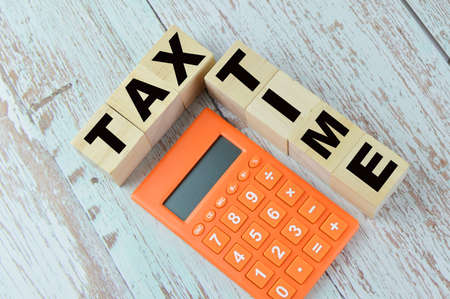 Top view of calculator and wooden blocks written with TAX TIME.の写真素材