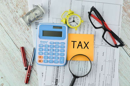 Top view of office tools and memo note written with TAX. Business concept.の写真素材