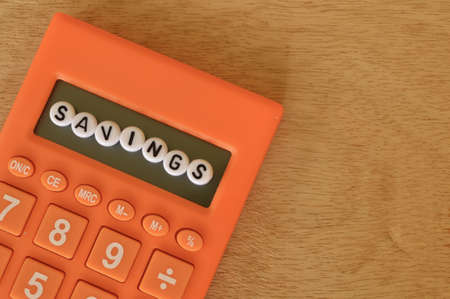 Top view of calculator and alphabet beads with text SAVINGS. Financial conceptの写真素材
