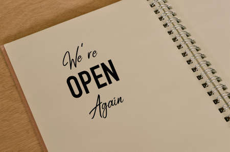 Phrase WE'RE OPEN AGAIN written on notebookの写真素材