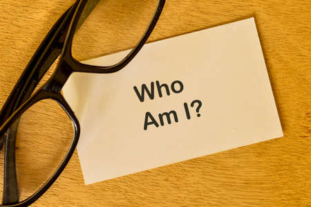 Phrase WHO AM I? written on white paper with eyeglasses.の写真素材