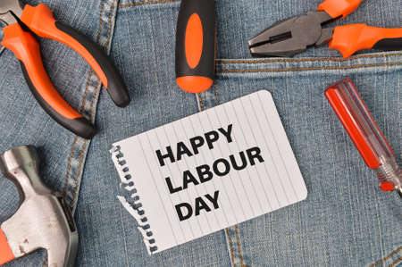 Phrase HAPPY LABOUR DAY written on white paper with hammer, screwdrivers and pliersの写真素材
