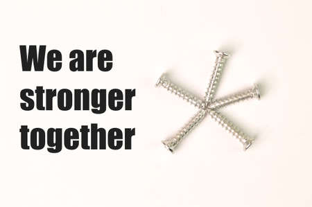 Phrase WE ARE STRONGER TOGETHER written on a white background with bunch of screwsの写真素材