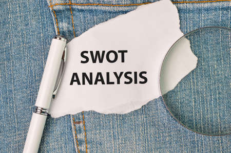 Phrase SWOT ANALYSIS written on white paper with pen and magnifying glass.の写真素材