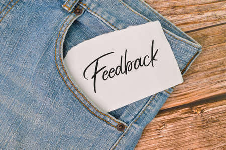 Phrase FEEDBACK written on white paper with blue jeans.