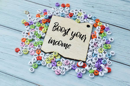 Bunch of alphabet beads and wooden board written with BOOST YOUR INCOME.の写真素材