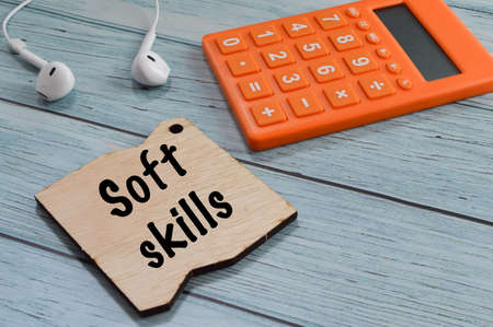 Selective focus of calculator, earphones and wooden board written with SOFT SKILLSの写真素材