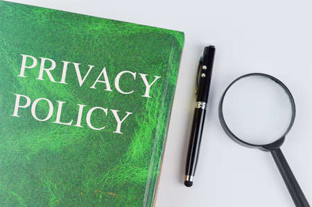 Top view of pen, magnifying glass and green book written with PRIVACY POLICY.の写真素材