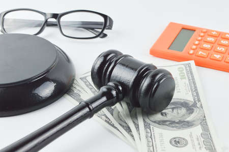 Selective focus of judge gavel, money banknotes, calculator and eyeglasses over white background