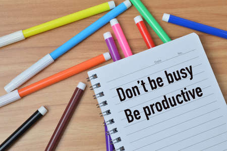 Top view of notebook written with DON'T BE BUSY BE PRODUCTIVE
