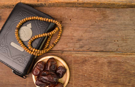 Bunch of dates, Islamic prayer beads and holy quran on wooden board with copy space. Ramadan kareem festiveの写真素材