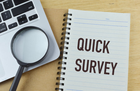 Top view of magnifying glass, laptop and notebook written with QUICK SURVEYの写真素材