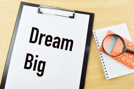 Top view of magnifying glass, calculator, notebook and white paper written with DREAM BIG.の写真素材