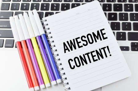 Top view of laptop, pen colors and notebook written with AWESOME CONTENT!