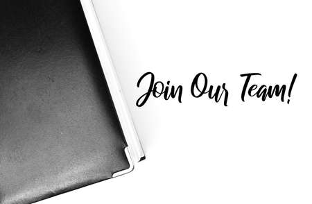 Top view of notebook over white background written with JOIN OUR TEAM