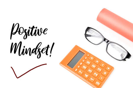 Top view of eyeglasses, calculator and colored paper over white background written with POSITIVE...