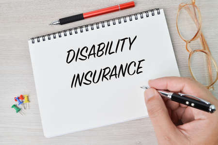 Hand holding pen and writing text DISABILITY INSURANCEの写真素材