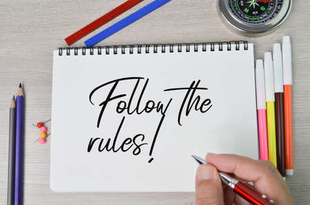 Hand holding pen and writing text FOLLOW THE RULES!の写真素材