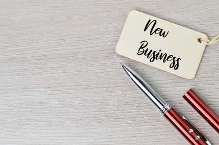 Top view of pen and label tag written with NEW BUSINESSの写真素材