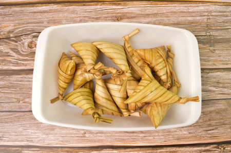 Ketupat palas or rice dumpling in a white plate. Ketupat palas is a natural rice casing made from...
