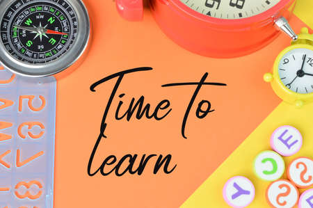 Stationery tools over red and yellow background written with TIME TO LEARN.の写真素材
