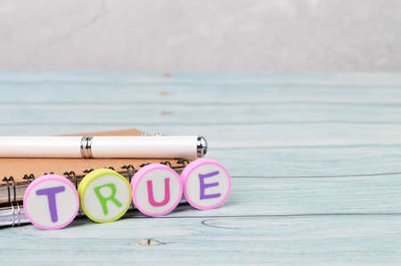 Pen and alphabet letters with text TRUE. Conceptual image