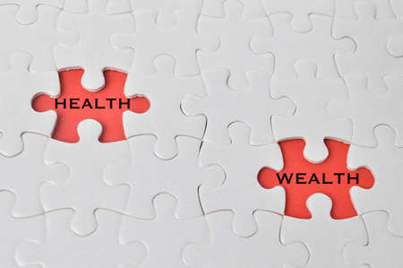 Top view of jigsaw puzzle isolated on red background written with HEALTH and WEALTH. Conceptual imageの写真素材