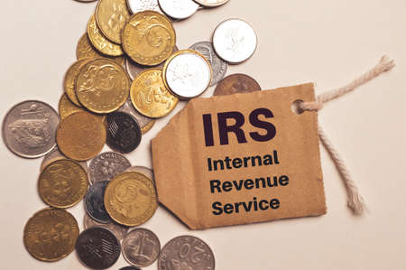 Top view stack of coins and label tag written with IRS stands for Internal Revenue Service. Business...