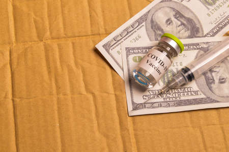 Top view of money banknotes, syringe and covid-19 bottle vaccination with copy space.