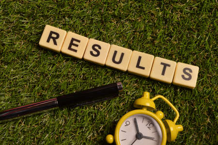 Top view of clock, pen and alphabet letters with text RESULTS.の写真素材