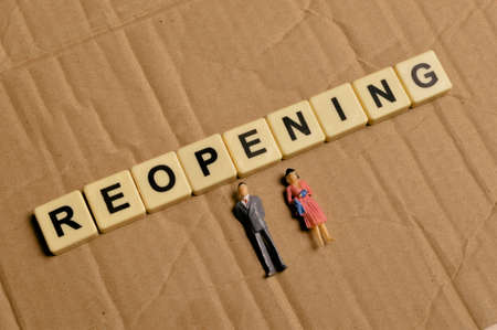 Top view of people miniatures and alphabet letters with text REOPENING.の写真素材