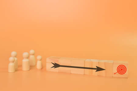 Wooden figures of people with a black arrow. Concept of movement to the goalの写真素材