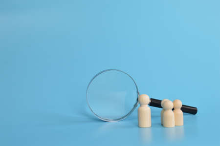 Wooden doll figures and magnifying glass. The concept of search for vacancies and work.の写真素材