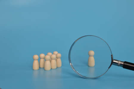 Magnifying glass is looking at the wooden figures of people