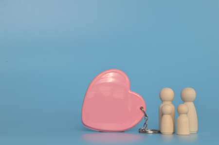 Wooden doll figures with love shape on blue background. Family love concept.の写真素材