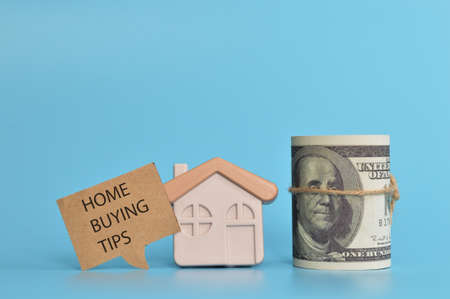 Toy house, money banknote and speech bubble note written with HOME BUYING TIPSの写真素材