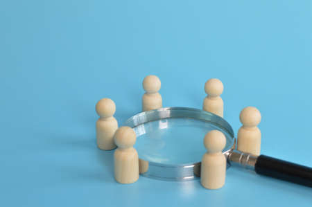 Wooden doll figures standing around magnifying glass. The concept of solving problemsの写真素材