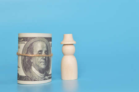 Wooden doll figures and money banknotes isolated on a blue backgroundの写真素材