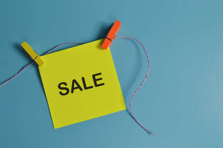 Top view of paper note written with SALE isolated on blue backgroundの写真素材