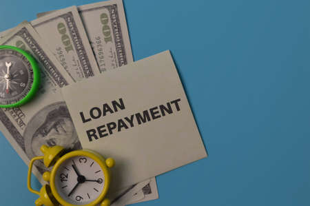 Clock, money banknotes and memo note written with LOAN REPAYMENT.Business conceptの写真素材
