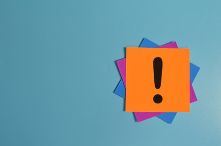 Exclamation mark drawn on memo note isolated on blue background. Copy spaceの写真素材