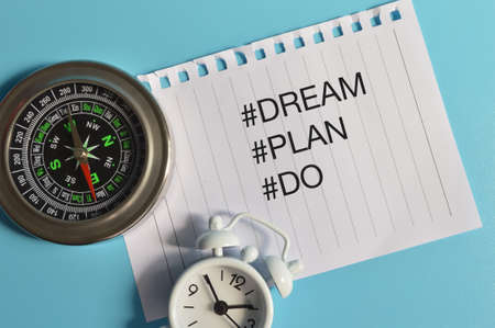 Top view of compass, clock and white paper written with hashtag DREAM, PLAN and DO