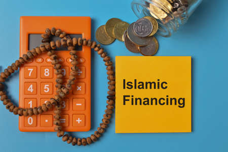 Top view of coins, rosary beads, calculator and memo note written with ISLAMIC FINANCING.の写真素材